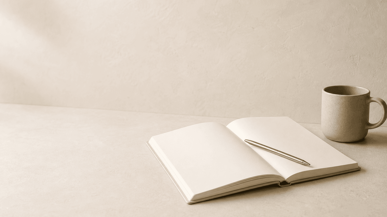Warm editorial still life with a notebook, pen, and ceramic cup