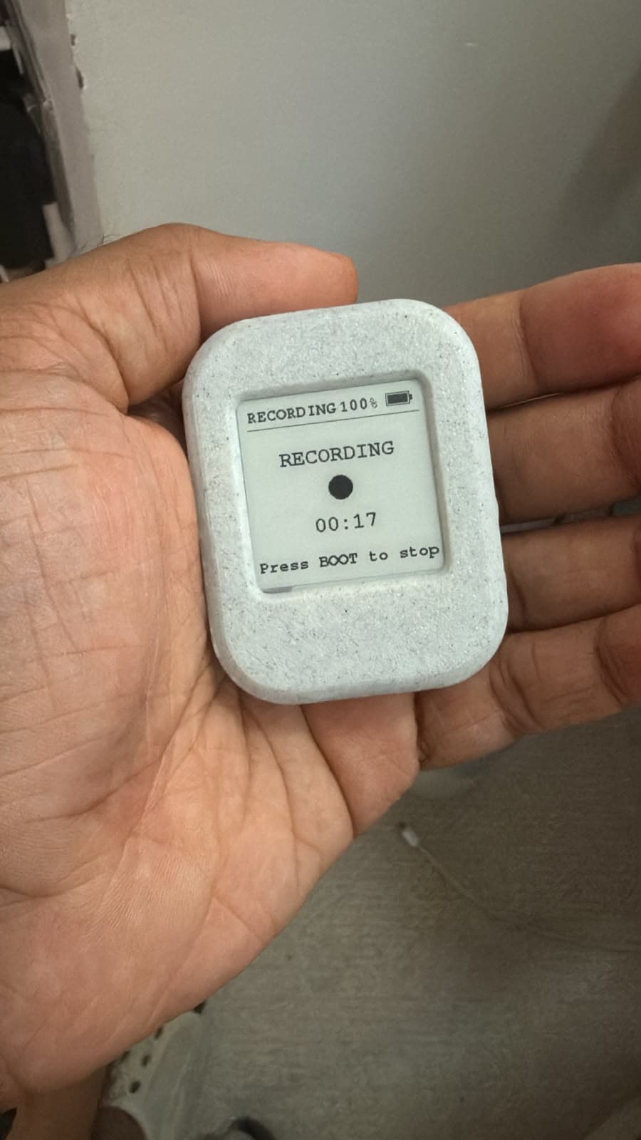 Early Aira hardware prototype held in a hand with its e-paper screen showing an active recording state